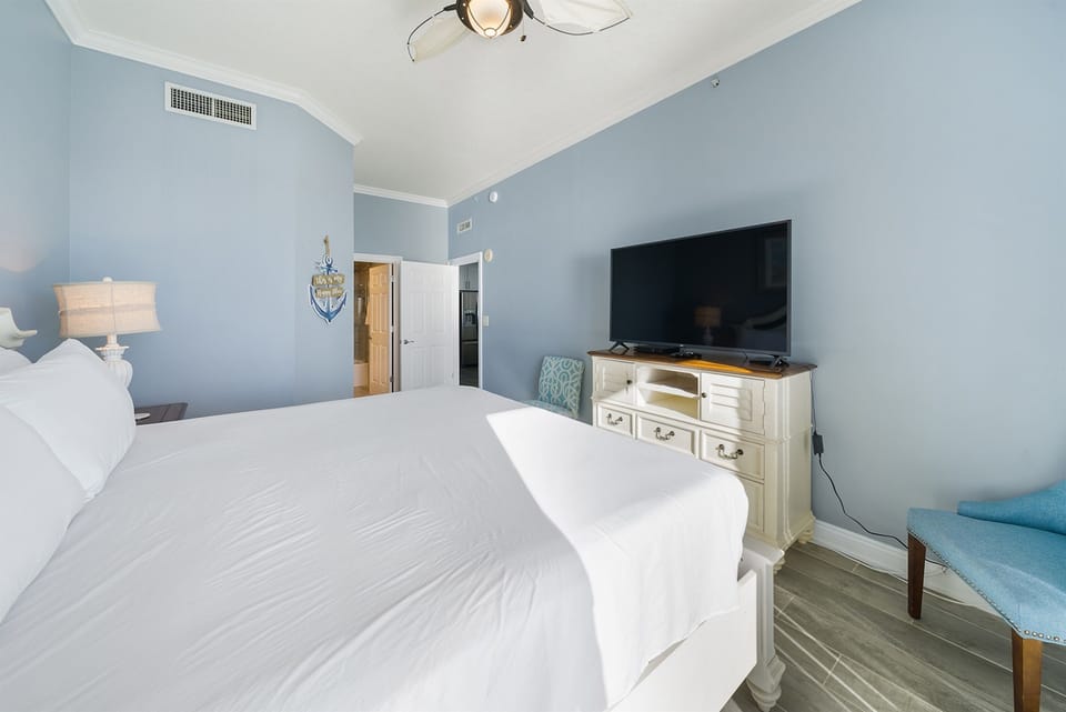 Sink into crisp white linens and coastal tranquility in your serene bedroom, complete with entertainment and peaceful blue walls.