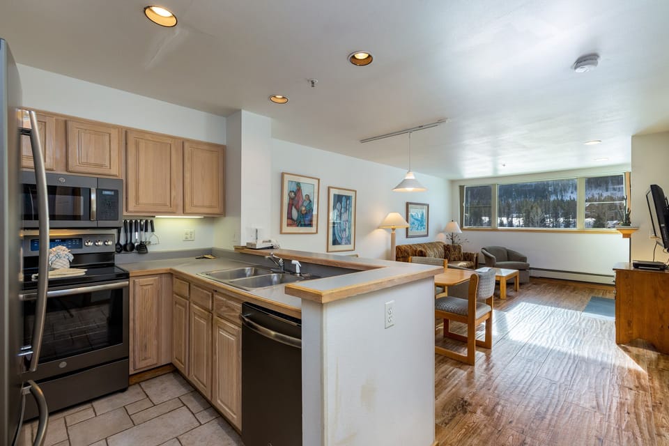 Your spacious kitchen flows seamlessly into the cozy living area, where natural light streams through large windows revealing mountain views.