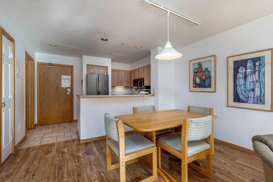 Gather around your warm wood dining table, perfectly positioned between the fully equipped kitchen and cozy living space for memorable meals together.