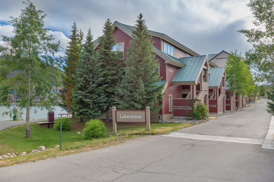 Lakeshore vacation rentals feature charming red cedar buildings nestled among tall evergreens, with convenient street access and nearby lake views.