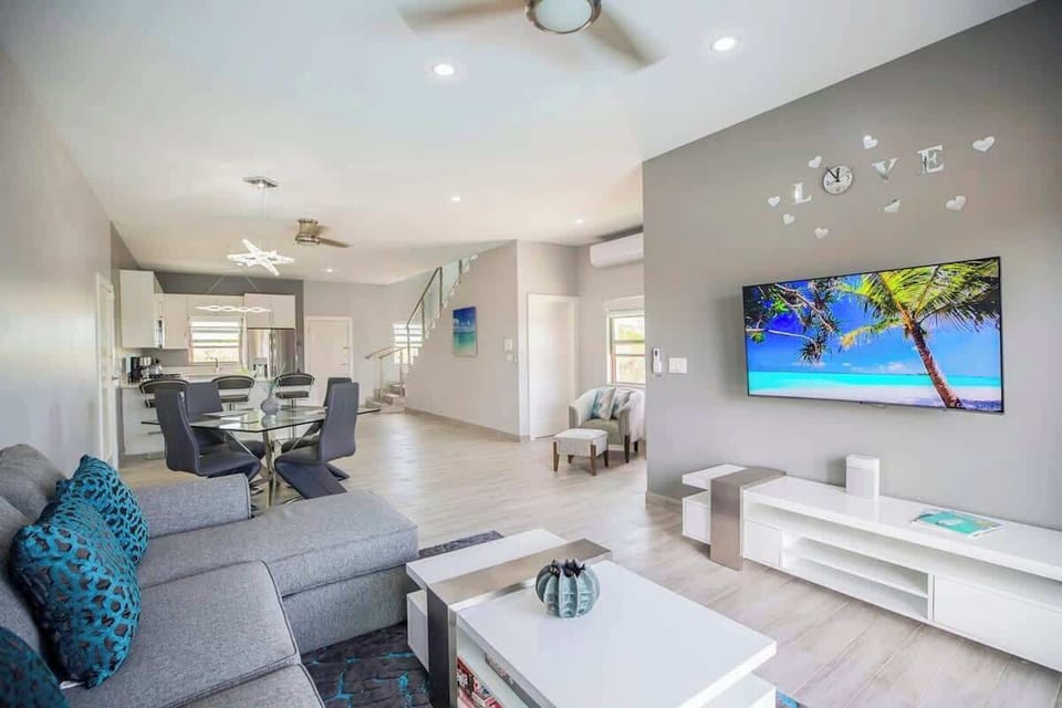The living room features a comfy sofa and a 55” Smart TV.