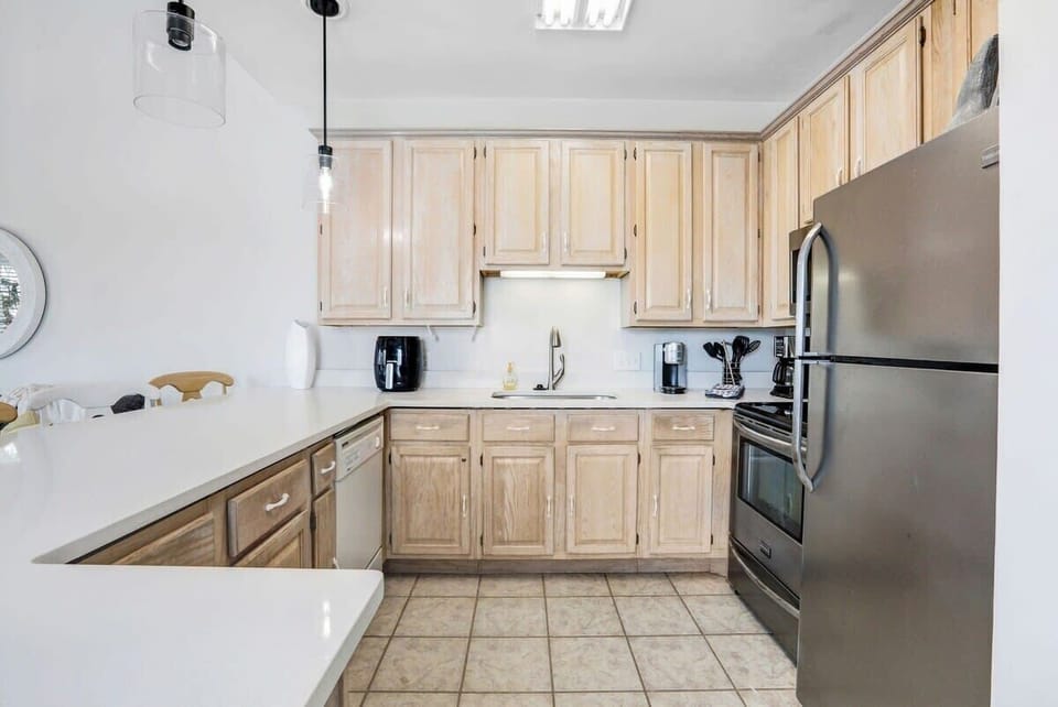 Well-equipped kitchen with stainless appliances and quartz counter. 
