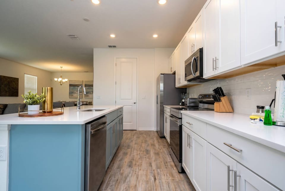 Experience this bright kitchen, where sleek white cabinetry pairs perfectly with the soft aqua island. Modern stainless steel appliances and fixtures make meal prep enjoyable in a warm, inviting atmosphere.