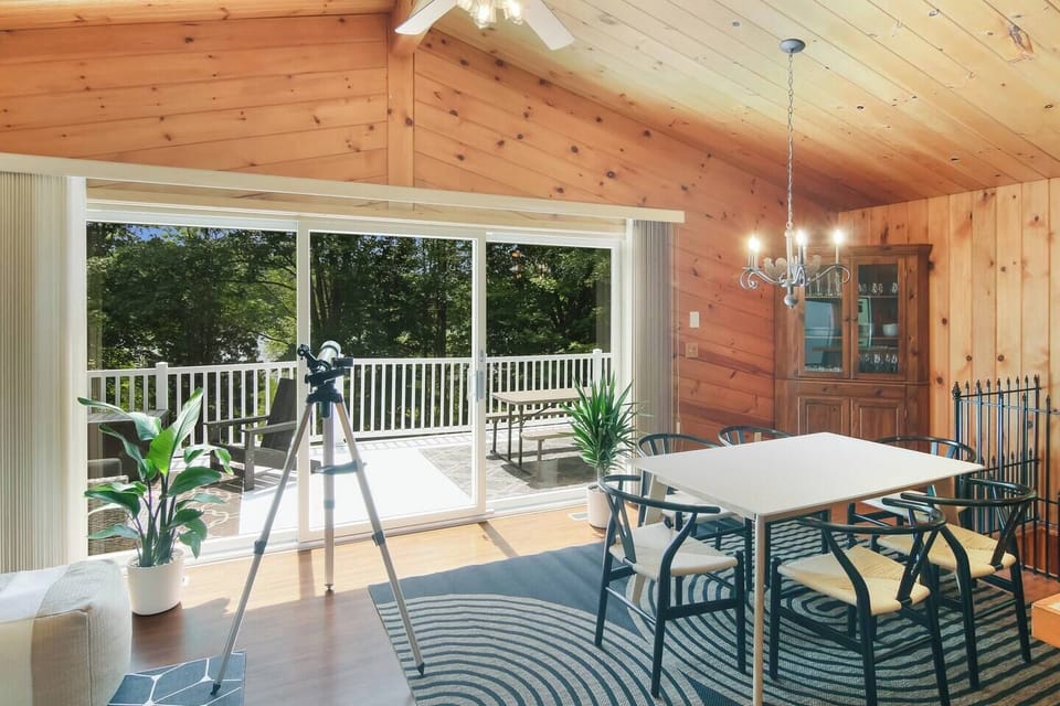 Dining table in a bright four-season room with forest views