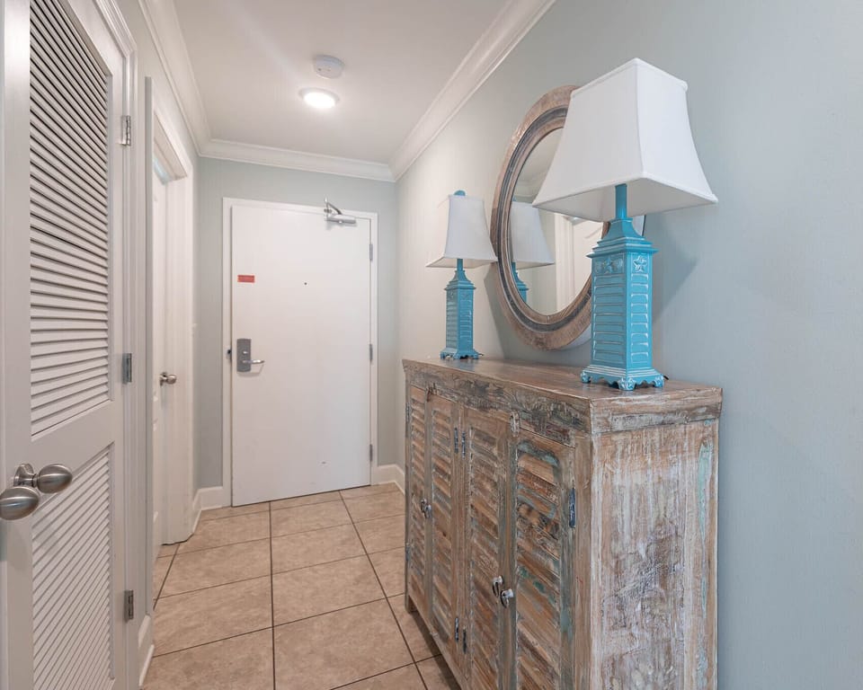 Step into this welcoming entryway featuring a rustic cabinet, bright lamps, and a round mirror that enhances the space