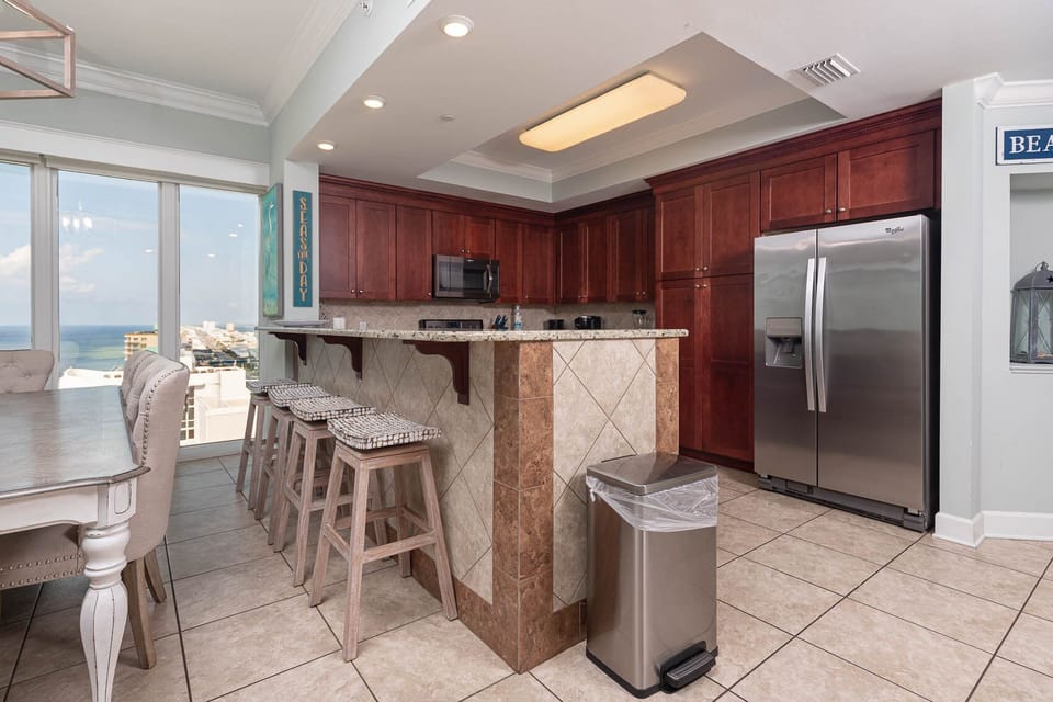 Gather around the dining table or breakfast bar in this inviting kitchen, featuring rich cabinetry and beach views