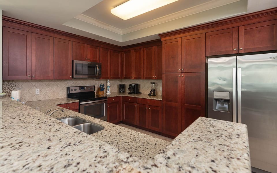 Cook and gather in this stylish kitchen, featuring rich cabinetry, granite countertops, and stainless appliances