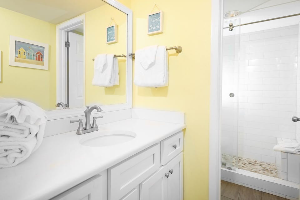 Sleek white vanity and a walk-in glass shower in the master bathroom, creating a cheerful and refreshing space