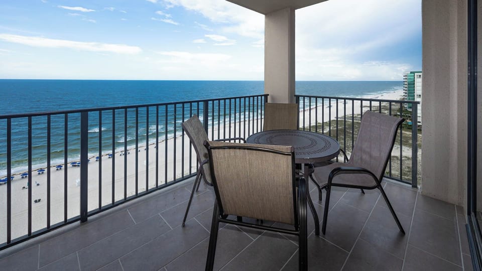 Relax at the outdoor table with chairs, enjoying views of the water and beach from your balcony