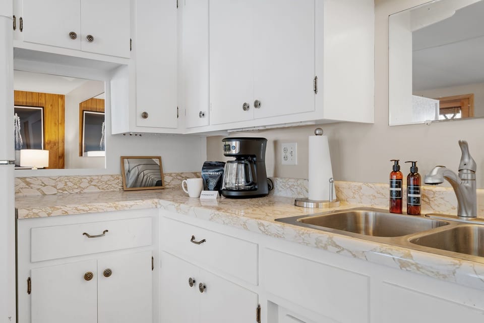 Whip up your morning brew in this bright kitchen featuring elegant marble countertops, crisp white cabinets, and thoughtful amenities.
