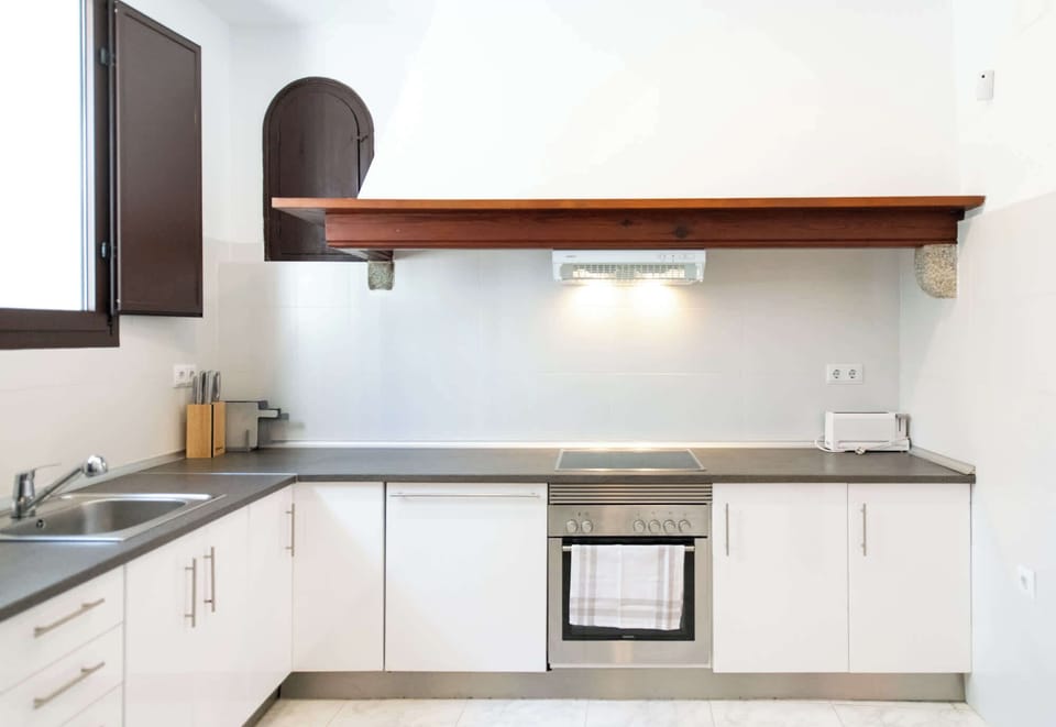 Sleek kitchen with white cabinets, stone counters, and wood beam accent
