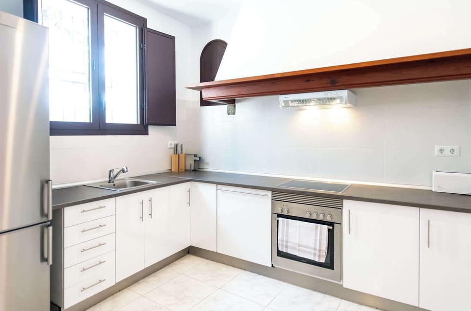 Bright modern kitchen with white cabinetry, wood shelf, and full appliances