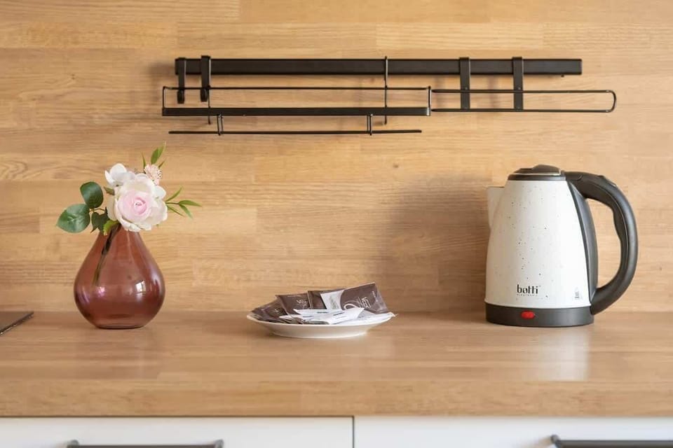 A wooden countertop with a kettle, mugs, and minimalist decor.
