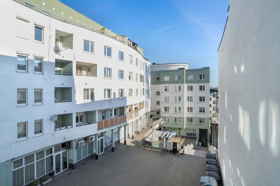 An exterior view of a modern residential building with a spacious courtyard.
