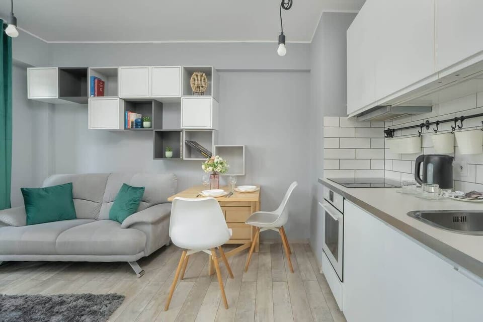 A wide shot combining the gray sofa, dining area, and sleek kitchen, all tied together by a modern aesthetic.
