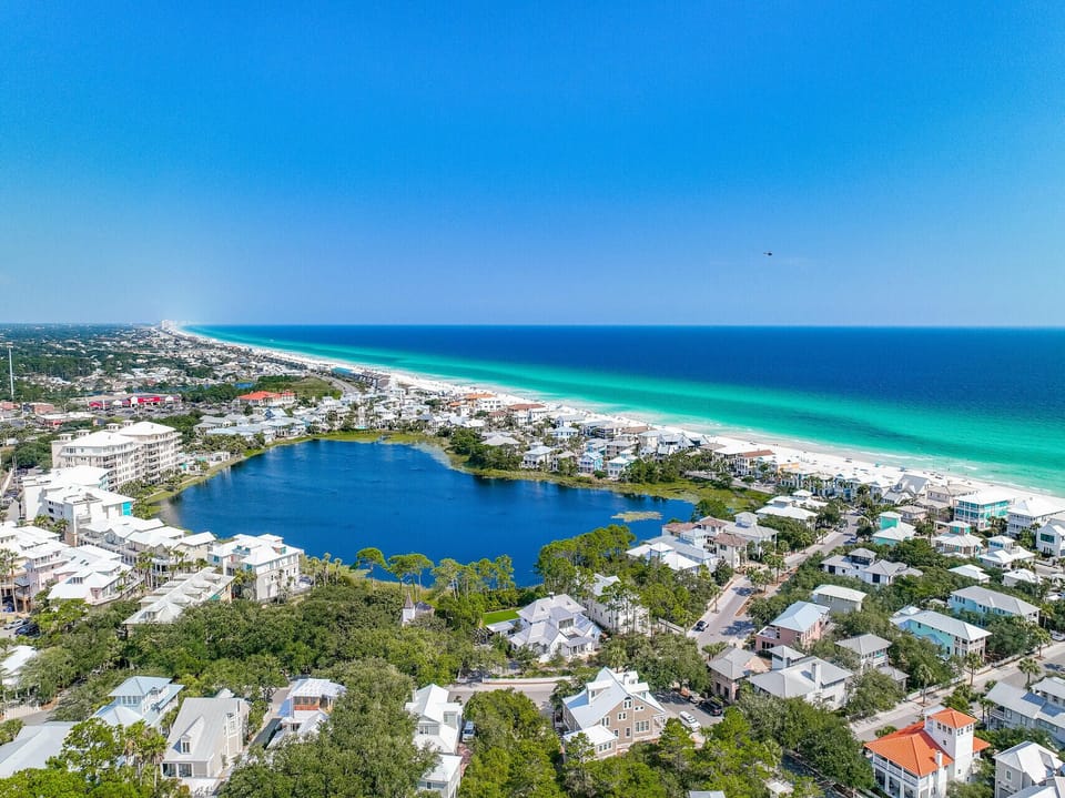 Stunning aerial view showcasing pristine beaches, turquoise waters, and charming coastal community with lake and residential areas.