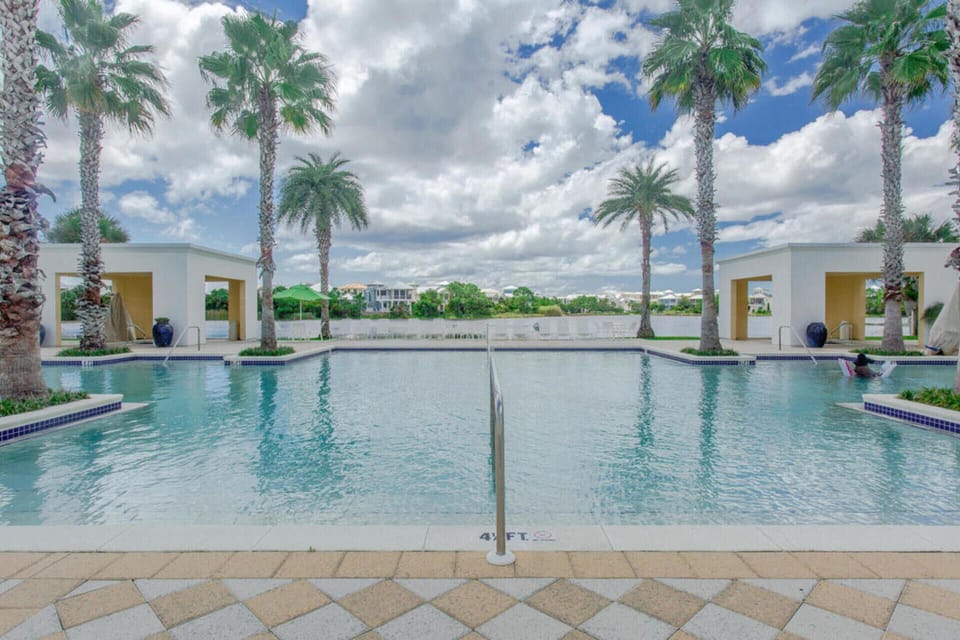 Resort-style swimming pool surrounded by swaying palms and modern pavilions under bright Florida skies.