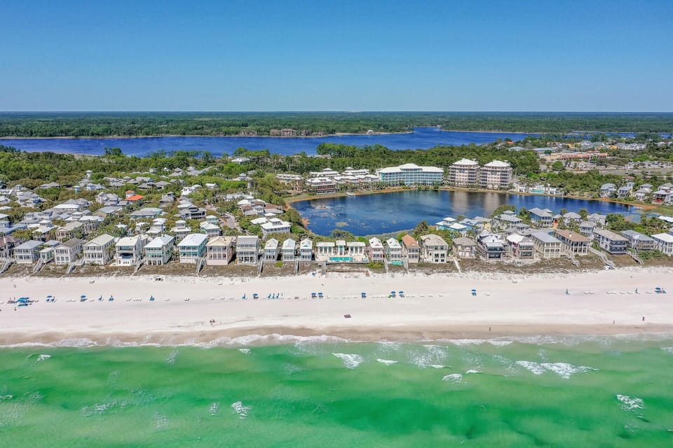 Stunning aerial view of beachfront properties along pristine emerald waters and white sand beach.