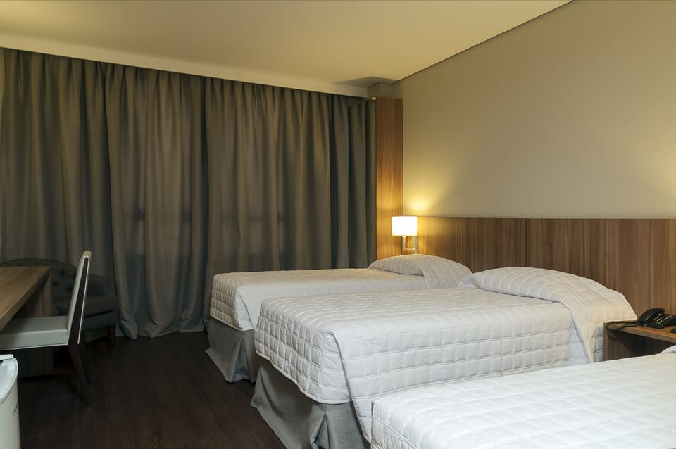 Deluxe Triple Room | Minibar, in-room safe, desk, blackout drapes