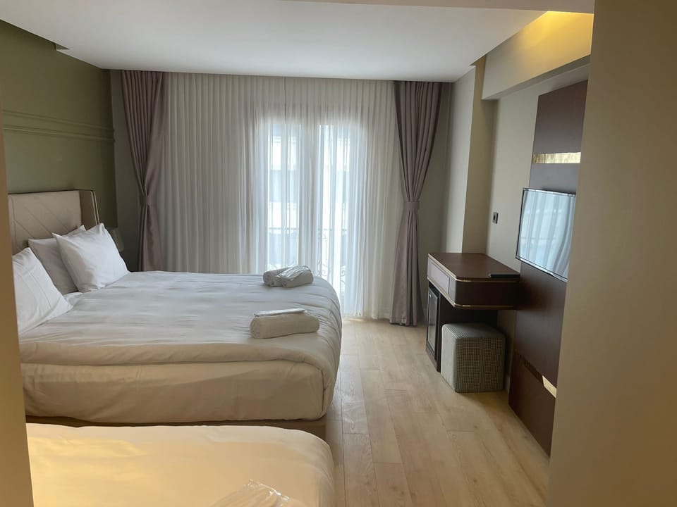 Deluxe Triple Room | Minibar, in-room safe, desk, laptop workspace