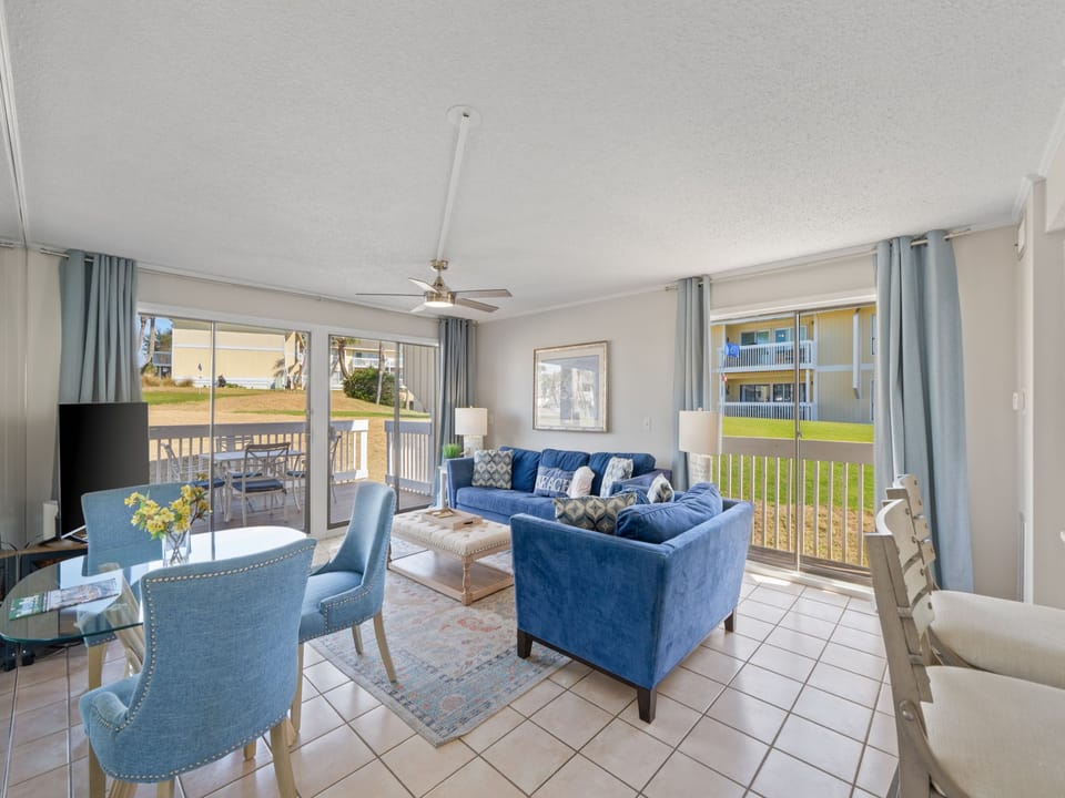This bright and open coastal living area offers comfortable seating, abundant natural light, and peaceful golf course views just outside. The open layout creates the perfect space for relaxing, gathering, and enjoying a laid-back beach getaway.