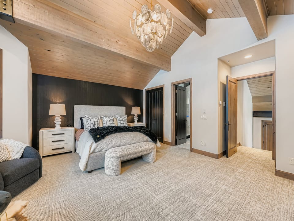 Unwind in your spacious master suite with vaulted wood ceilings, elegant chandelier, and cozy seating area - your perfect retreat after a day of adventure.