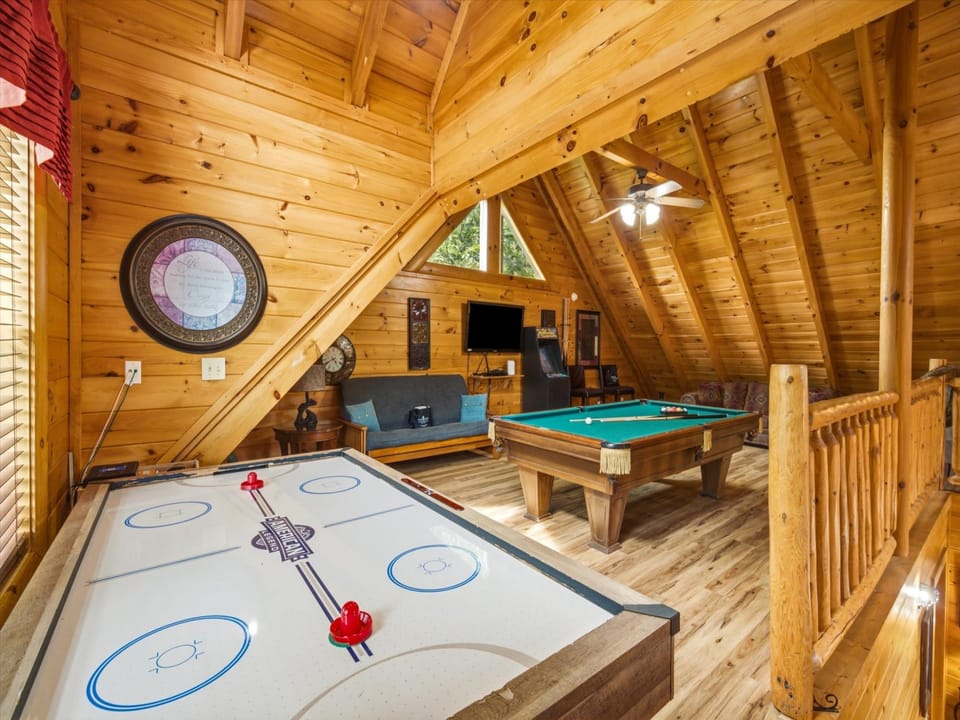 Your own private game loft awaits, with soaring wood-beamed ceilings, a billiards table, air hockey, and cozy seating—perfect for friendly competitions and laughter-filled evenings.