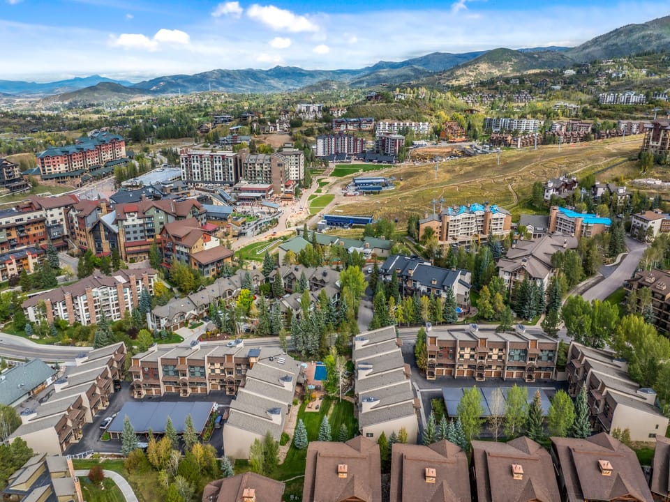 Aerial view of a mountain resort community surrounded by natural landscape and distant peaks.