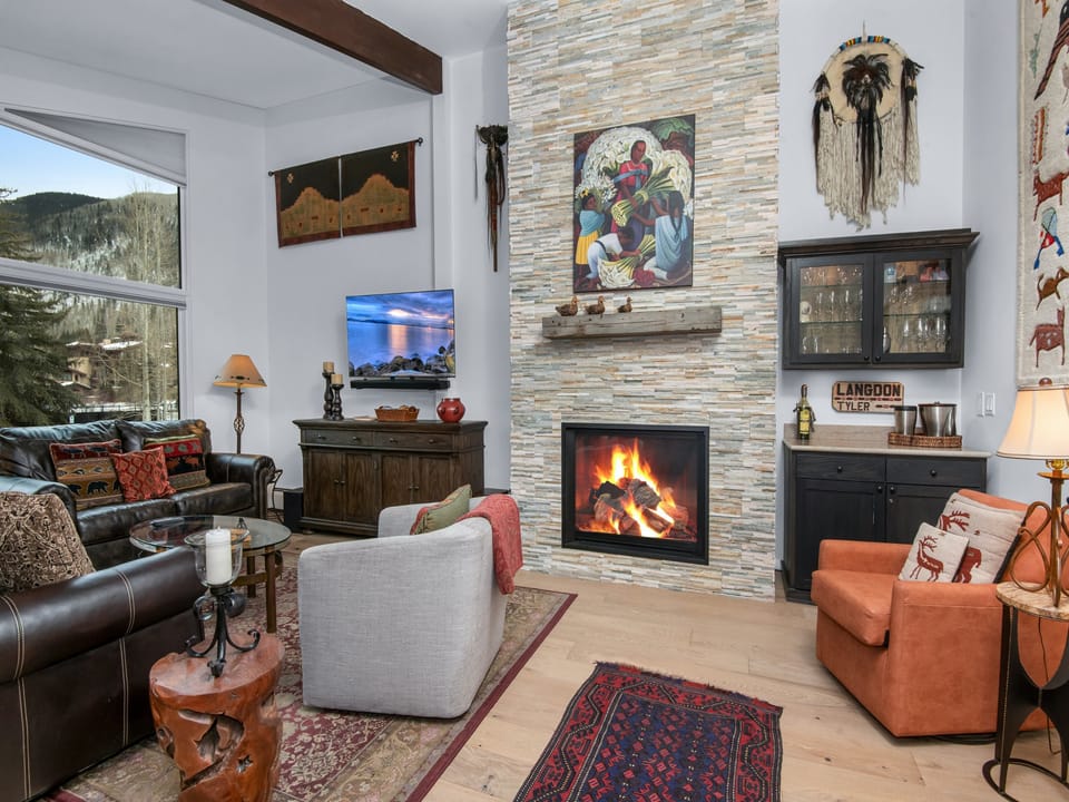 Curl up in your cozy living room where a crackling fireplace warms the space and mountain views frame your perfect alpine retreat.