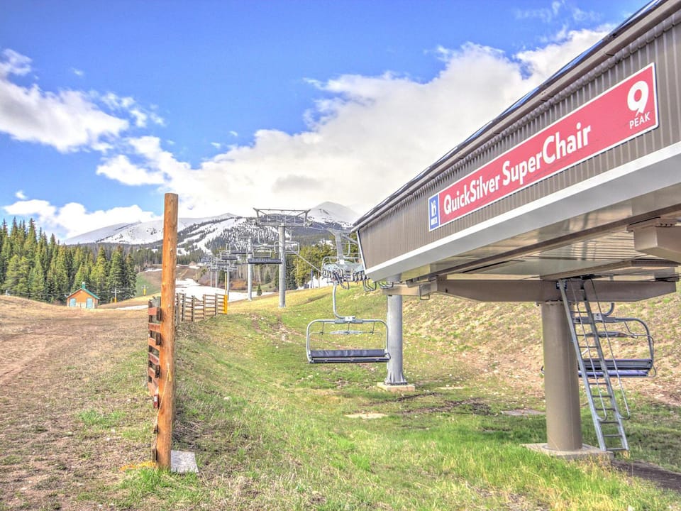 An outdoor scene of a ski resort with a chairlift labeled "QuickSilver SuperChair" against a backdrop of mountains and trees under a partly cloudy sky.