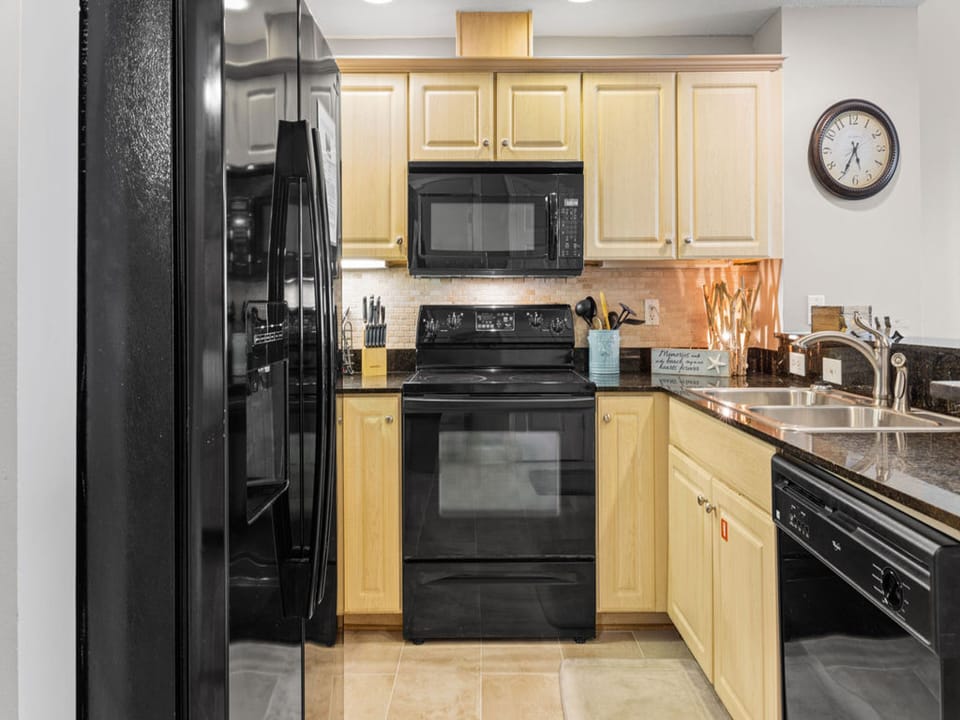 Managing meals will be a breeze in this fully stocked kitchen featuring black appliances, and all items needed for meal prepping.