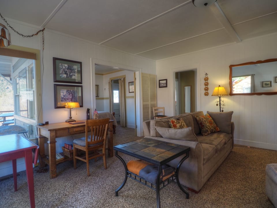 Murphy's Riverside Cottage - View of the cozy living area that has a desk, couch and overstuffed chair