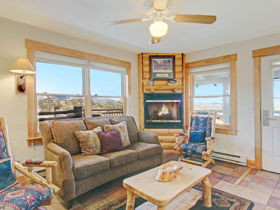 Ptarmigan Mountain 202 - Condo's main living area, three-cushion sofa, log rocking chairs, beautiful stone gas fireplace - windows let in beautiful mountain views.