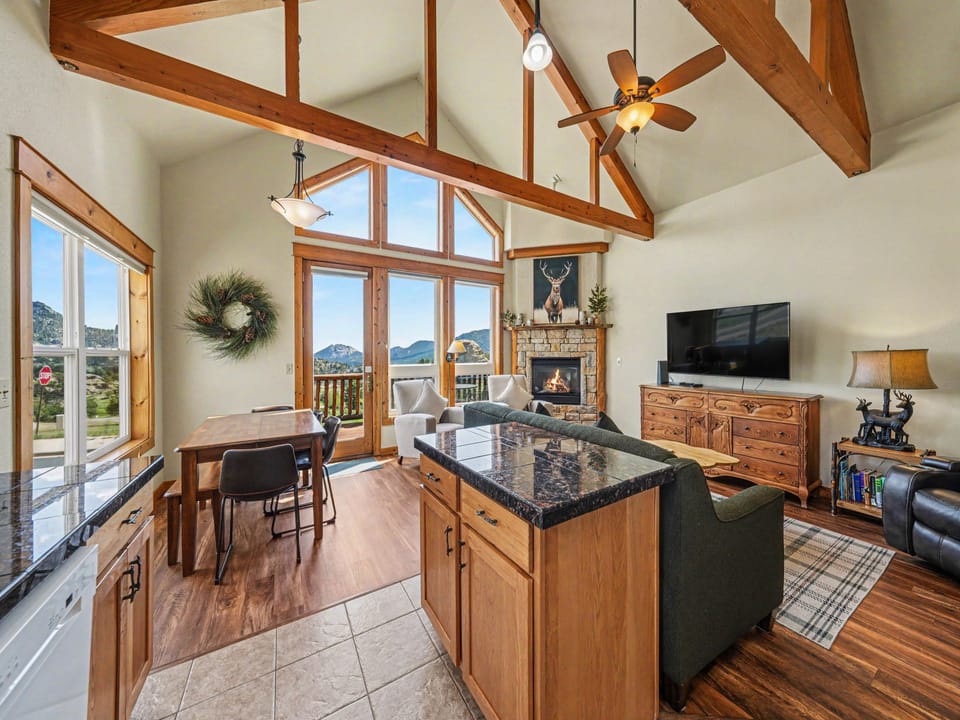 Soaring ceilings with exposed beams frame stunning mountain views through floor-to-ceiling windows. You'll love gathering around the cozy stone fireplace or preparing meals at the granite kitchen island in this airy, light-filled space.