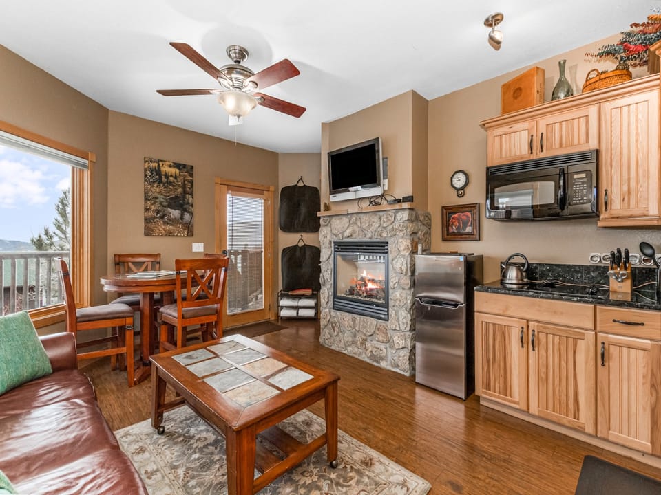 Deer Mountain 28B - Living/dining area with queen sleeper sofa and bar-height dining table (seating for four), gorgeous stone gas fireplace. Opens up to efficiency kitchen.