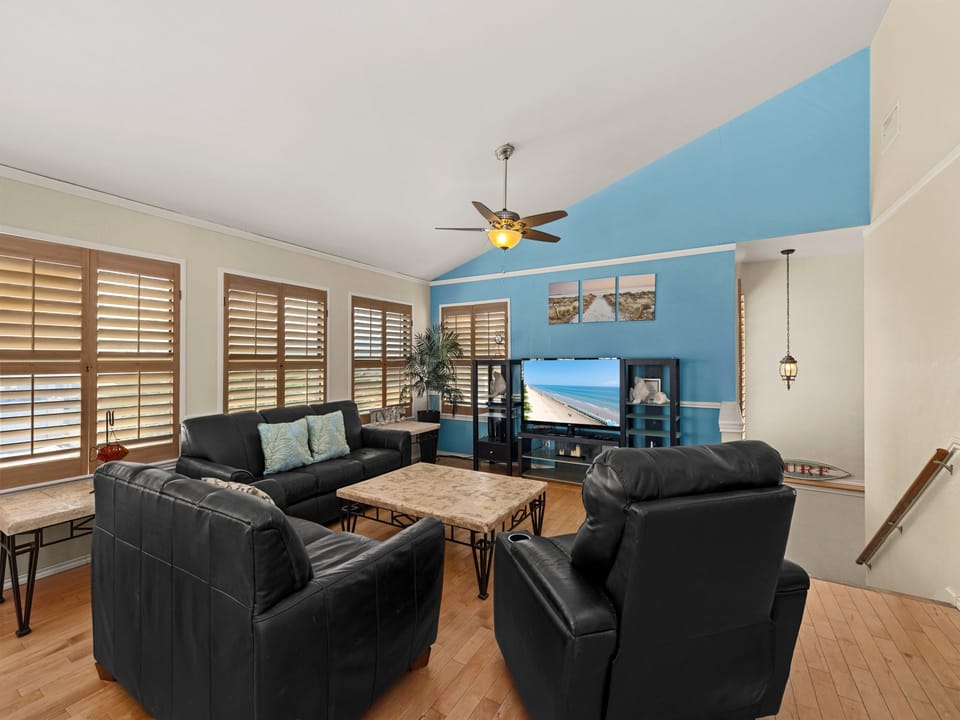 The spacious 2nd-floor living area offers a full-size sofa, a cozy loveseat, and a standard futon — with the futon sleeping 2 guests and the couches available for additional sleeping arrangements.