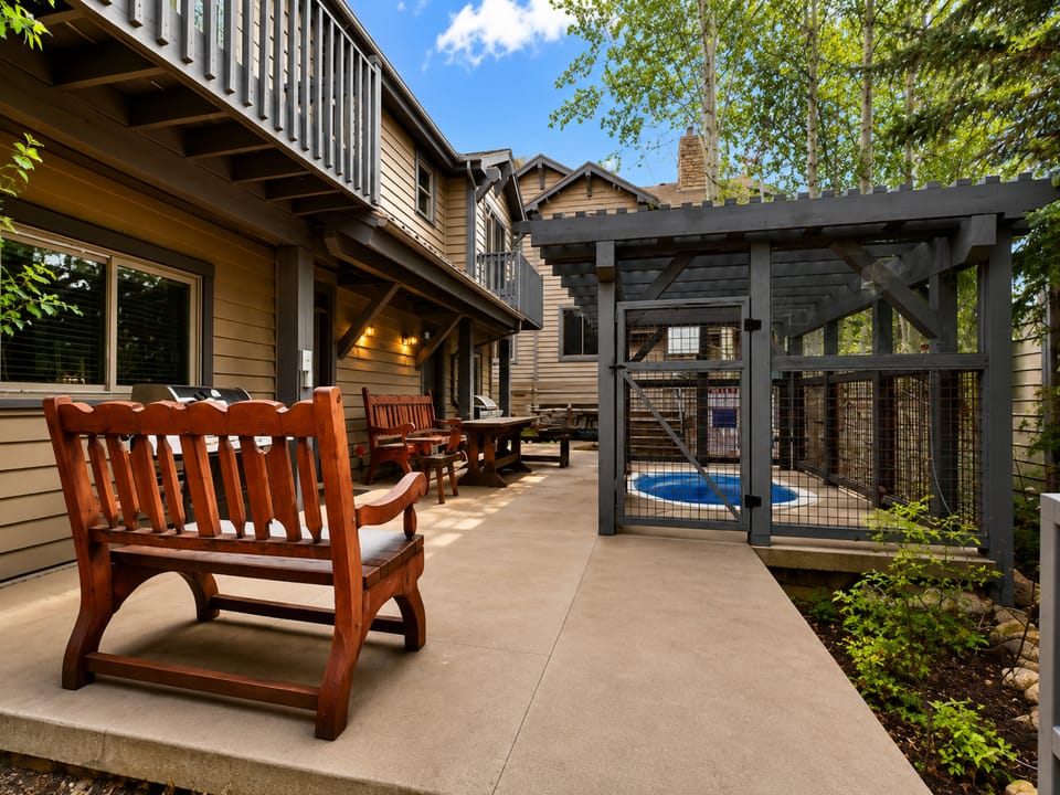 This welcoming outdoor space features rich wooden benches, a covered pergola, and direct pool access—your private retreat for sunny afternoons and leisurely evenings under the trees.