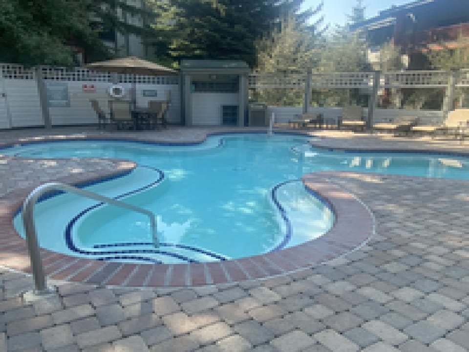 The property features a refreshing outdoor swimming pool area with paved surroundings for a comfortable and relaxing vacation experience.