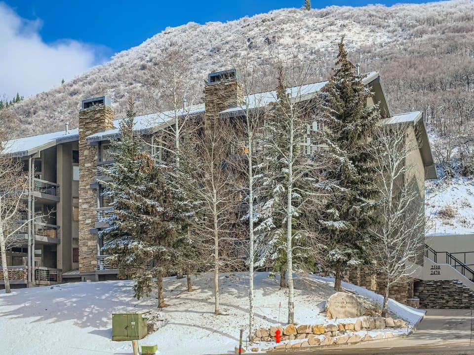 Modern mountain property nestled in a pristine winter landscape with snow-covered peaks and frosted trees creating a scenic alpine setting.