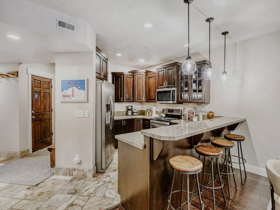 Your fully equipped kitchen features rich wood cabinetry, granite countertops, stainless steel appliances, and a breakfast bar with seating—perfect for preparing meals and gathering with friends.