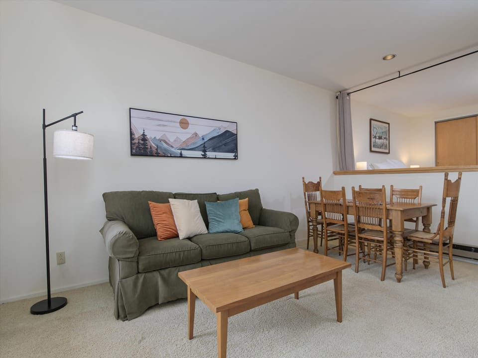 Relax in your comfortable living space with plush seating, a wooden coffee table, and a dining area perfect for family meals or game nights.