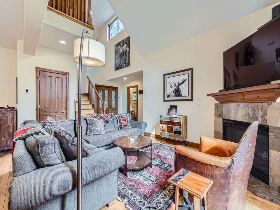 Sink into plush seating by your crackling stone fireplace, where soaring ceilings and warm wood touches create the perfect mountain retreat for cozy evenings with loved ones.
