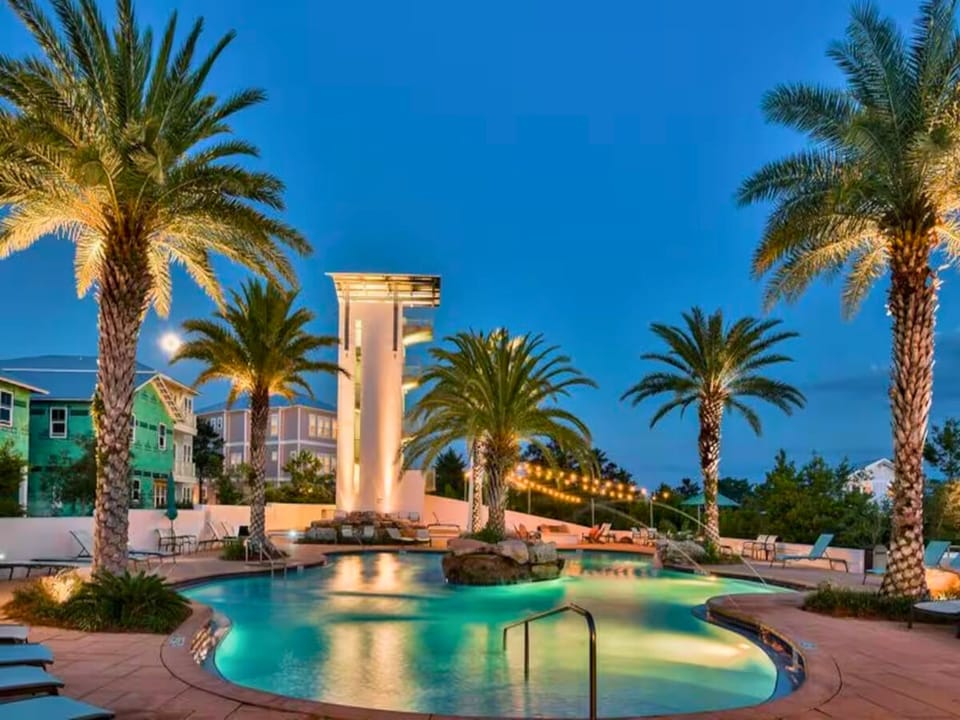 Tropical paradise awaits with illuminated palm trees surrounding your pristine pool oasis at twilight.