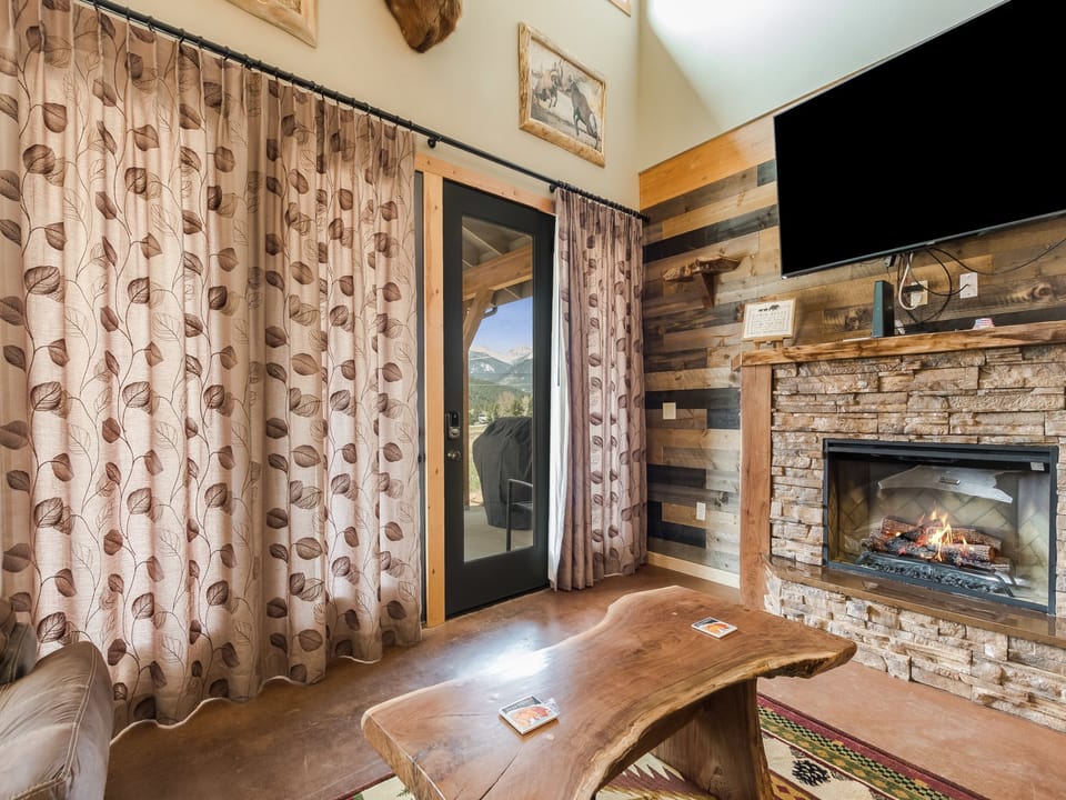 Show Me Mountain Views - The living area features a large flatscreen TV, a fireplace, rustic wooden accent furniture, and comfy couches