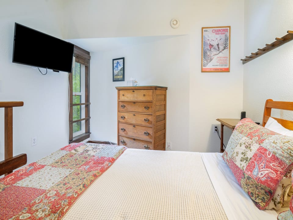 Sink into a cozy bed with cheerful quilted accents, enjoy your favorite shows on the wall-mounted TV, and store your belongings in the charming wooden dresser.