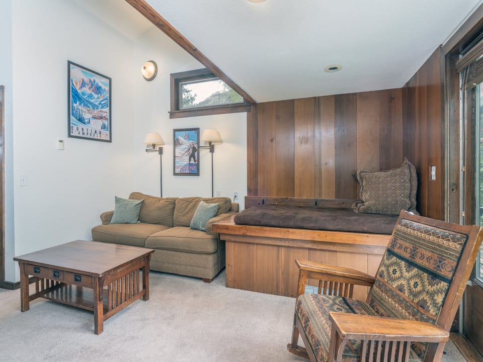 Unwind in your cozy living space with mountain charm, featuring warm wood tones, vintage ski art, and comfortable seating where you can relax after a day of adventure.
