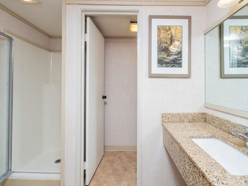 Step into your private bathroom featuring a spacious walk-in shower, granite countertops, and plenty of natural light to start your mornings right.