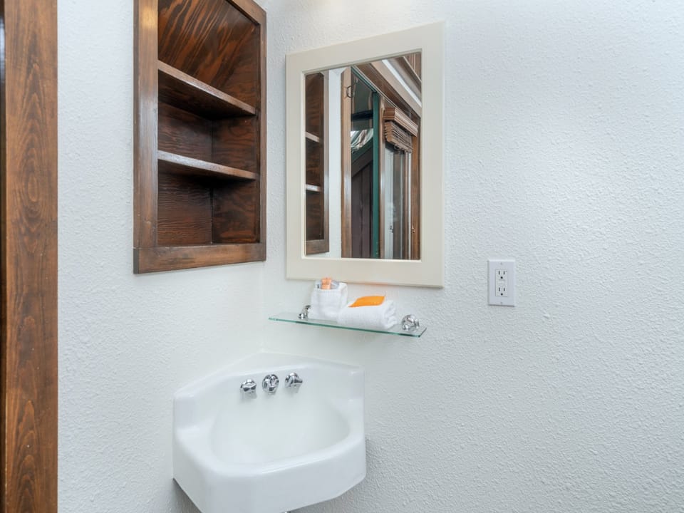 Freshen up at your charming corner sink with custom wood shelving and thoughtful touches that make every moment feel like home.