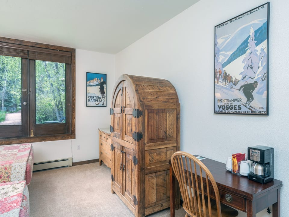 Your cozy corner features a distinctive wooden armoire and vintage ski posters that capture the alpine spirit, with a workspace and coffee maker for your convenience.