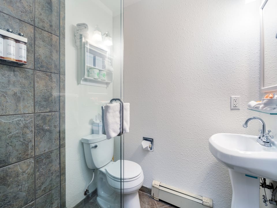 Your private bathroom features a walk-in shower with elegant stone tile, bright lighting, and all the essentials to refresh after a day of exploring.